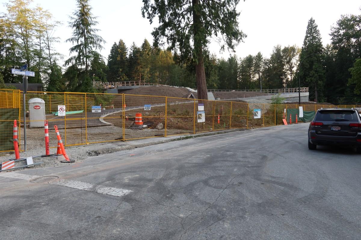 Overpass on the north side. Ramp to the overpass is paved. Overpass is behind a yellow construction fence.